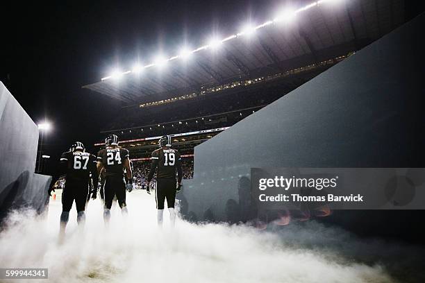 football team walking out of stadium tunnel - campo de fútbol americano fotografías e imágenes de stock