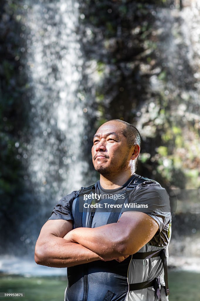 A man in his fifties standing near a waterfall