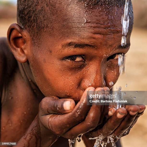 african young boy drinking fresh water on savanna, east africa - thirsty stock pictures, royalty-free photos & images