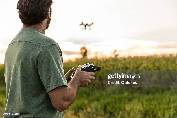 hombre volando un dron al atardecer - remote controlled fotografías e imágenes de stock