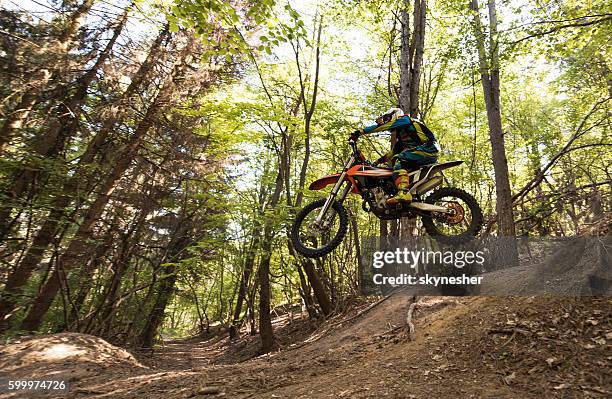 motocross rider in mid air while riding downhill in nature. - route moto stock pictures, royalty-free photos & images