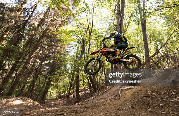 motocross rider in mid air while riding downhill in nature. - motocross imagens e fotografias de stock