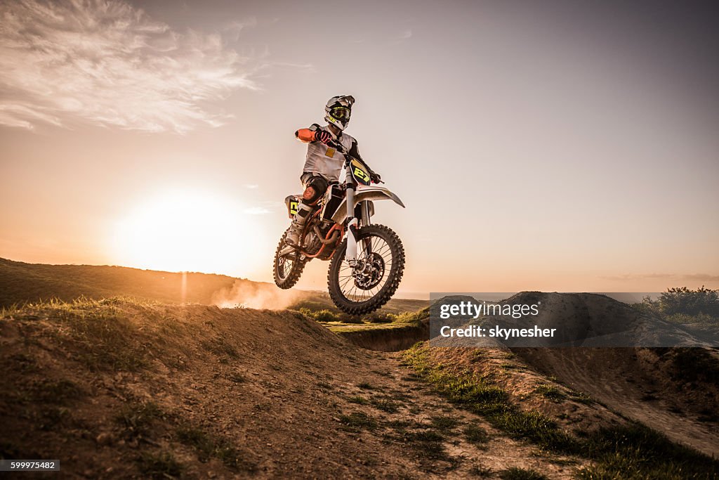 Dirt Bike Racer bei Sonnenuntergang Durchführung Sprung auf Feldweg.