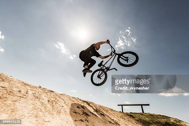 below view of bmx cyclist jumping against the sky. - bmx freestyle stock pictures, royalty-free photos & images
