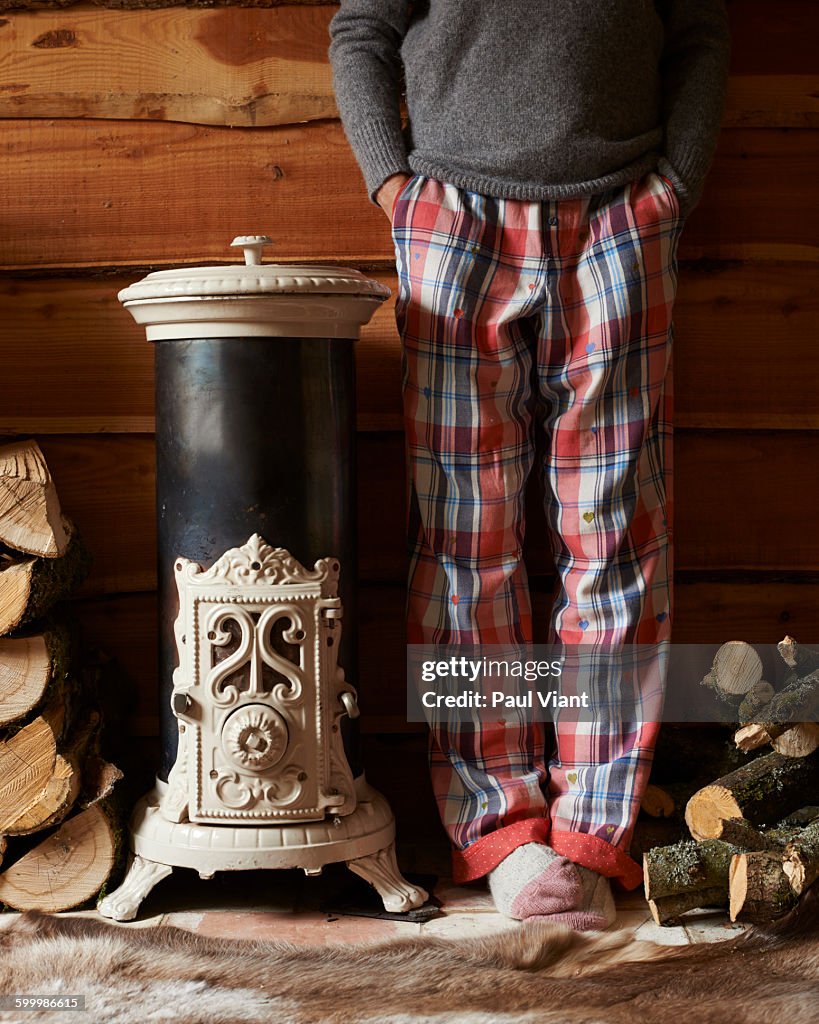 Woman in pyjamas by log vintage burner