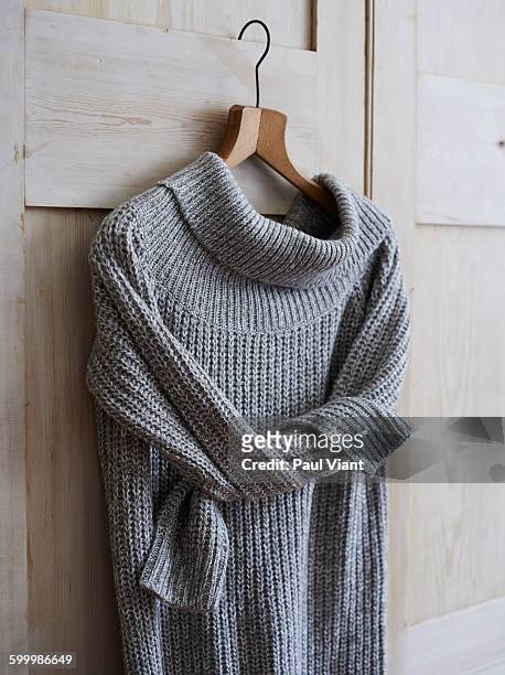 long knitted jumper on wooden coat hanger - maglione foto e immagini stock
