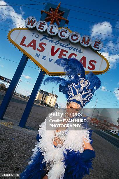 British show girl in front of a welcome to Las Vegas sign.