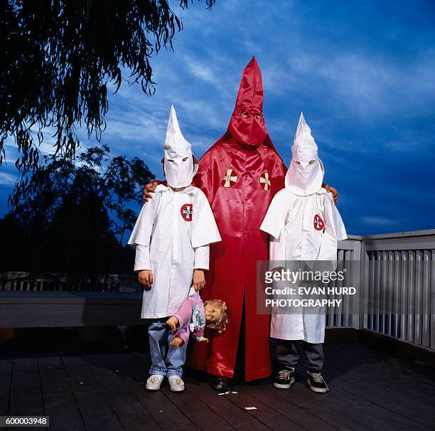 Member of the Ku Klux Klan and his two children wearing traditional Klan clothes.