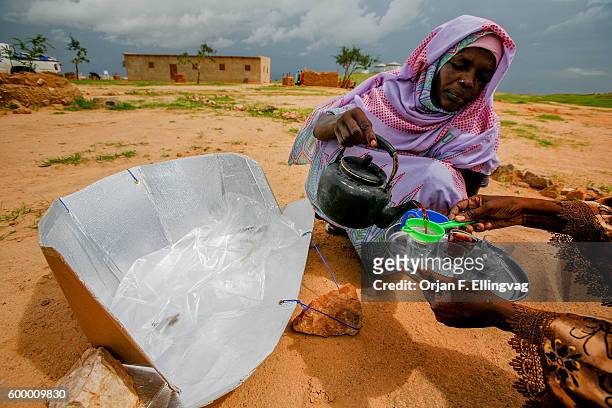 Woman pours tea in a refugee camp in Iridimi in Tchad, close to the sudanese border. The tea is boiled in a solar cooker, fabricated by women in the...