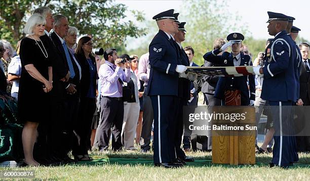 Left, Terry Harmon, stands with family members and friends as members of the U.S. Air Force honor guard folds the U.S. Flag over the remains of her...