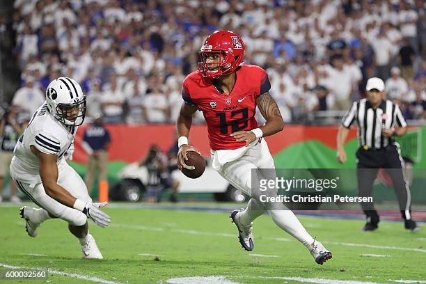 Quarterback Anu Solomon of the Arizona Wildcats scrambles to pass under pressure from defensive back Kai Nacua of the Brigham Young Cougars during...