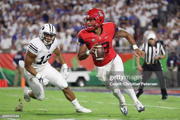 Quarterback Anu Solomon of the Arizona Wildcats scrambles to pass under pressure from defensive back Kai Nacua of the Brigham Young Cougars during...