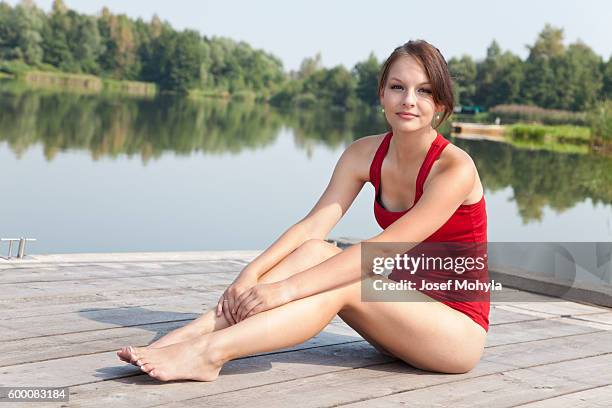 yong woman sitting on pier over pond - josef mohyla stock pictures, royalty-free photos & images