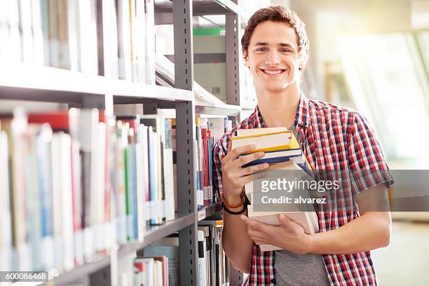 young student with books in library - male student stock pictures, royalty-free photos & images