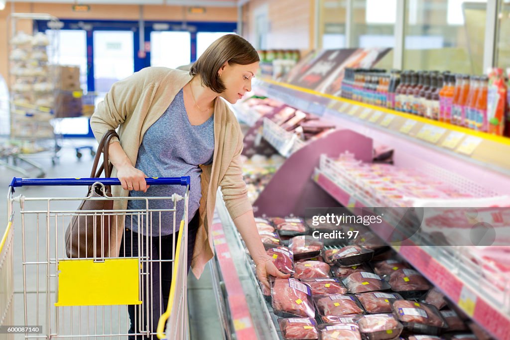 Pregnant woman chooses meat in the store