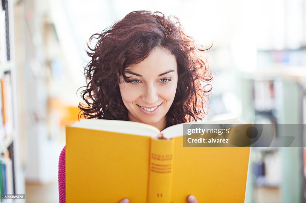 Joven que lee un libro en la biblioteca