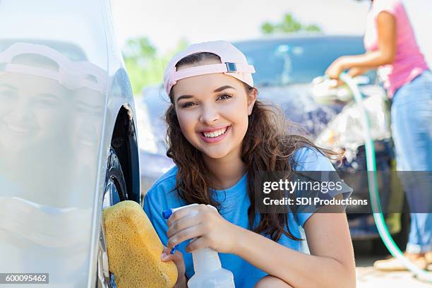 cheerful teenage girl washes car during fundraising event - teen wash car stock pictures, royalty-free photos & images