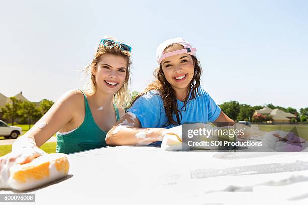 caucasian teenage girls wash car together during fundraiser - teen wash car stock pictures, royalty-free photos & images