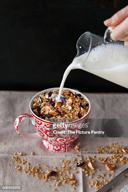 almonds and cranberries homemade granola in a cup with milk pouring from a jar - almond oil stock pictures, royalty-free photos & images