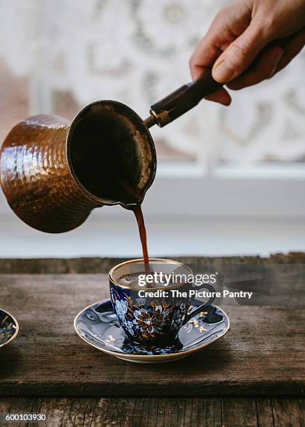 a woman is pouring turkish coffee in to a vintage turkish coffee cup. - turkish coffee fotografías e imágenes de stock