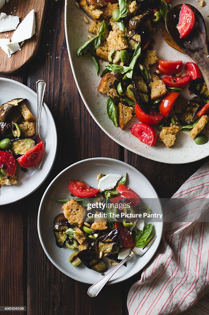 Roasted eggplant panzanella with capers, olives, and pine nuts, gluten-free.