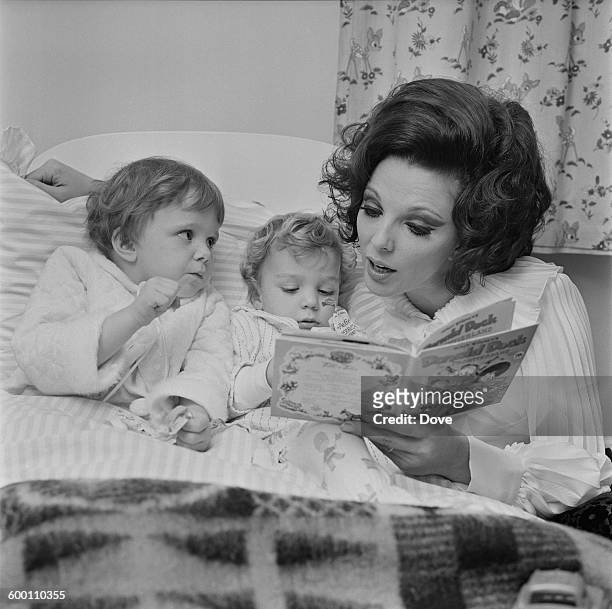 English actress Joan Collins, the wife of actor and singer Anthony Newley, reading a Donald Duck book to their two children Tara and Sacha, UK, 18th...