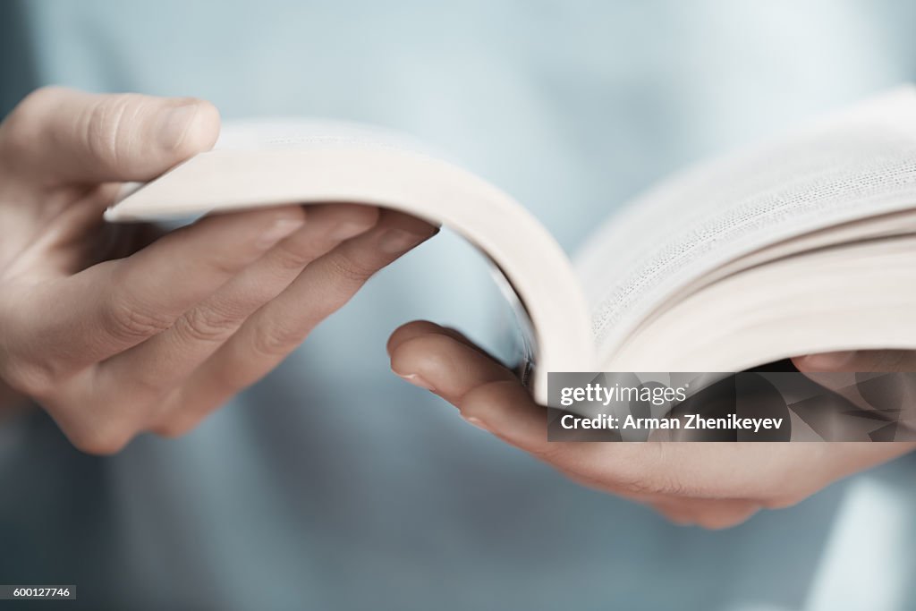 Man holding and reading book in library