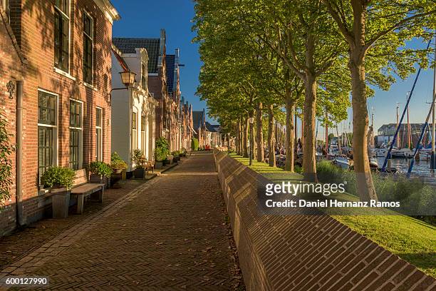 empty street in muiden at sunset with typical dutch houses on the left and a harbour on the right. the netherlands - 荷蘭北部 個照片及圖片檔