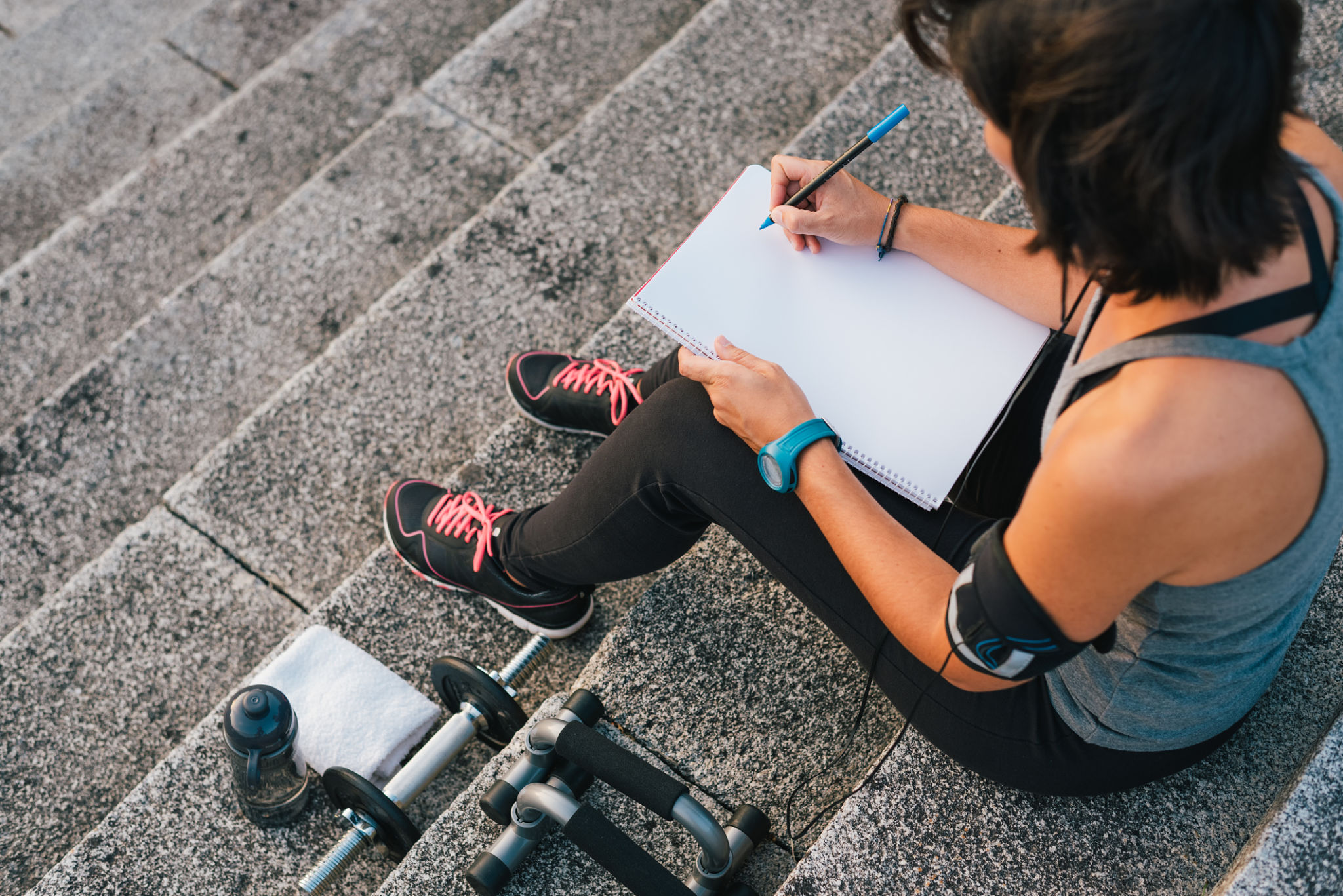 Urban female athlete focusing on her goals writting on notepad Urban female athlete focusing on her goals writting on notepad