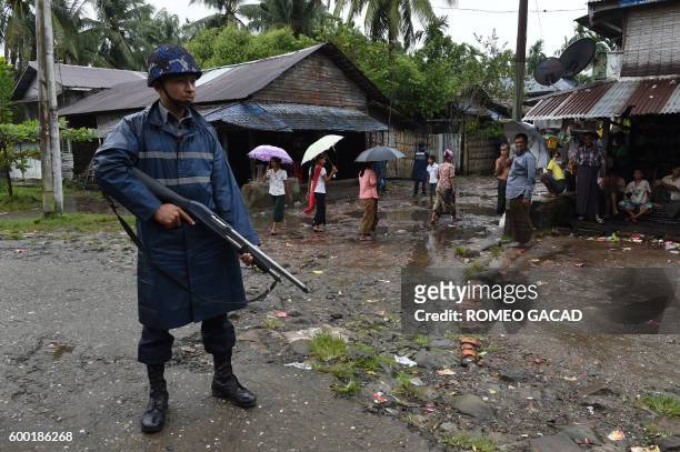 In this photograph taken on September 7 an armed police is posted on a road during a visit of former UN secretary general Kofi Annan Muslim Rohingya...