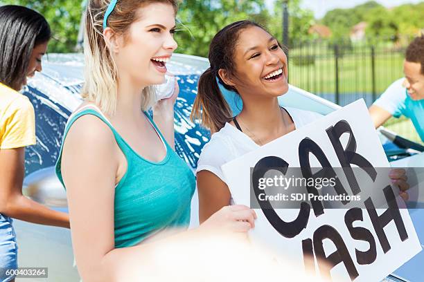 fun friends hold 'car wash' sign to promote the event - teen wash car stock pictures, royalty-free photos & images