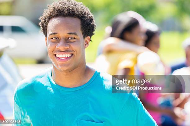 confident african american teenager participates in car wash fundraiser - male volunteer stockfoto's en -beelden