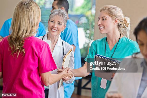young intern greets nurse during staff meeting - meet and greet stock pictures, royalty-free photos & images