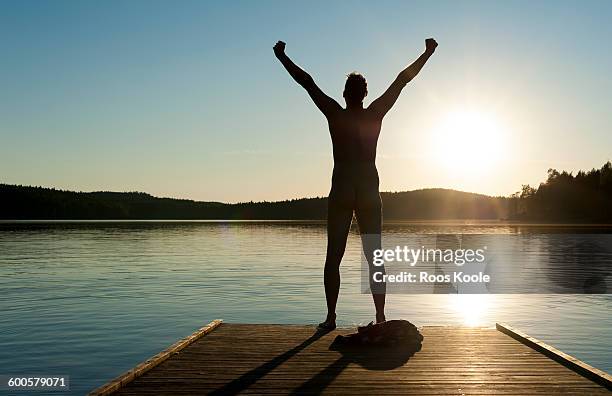 a man stretches his arms on a jetty - birthday suit stock-fotos und bilder