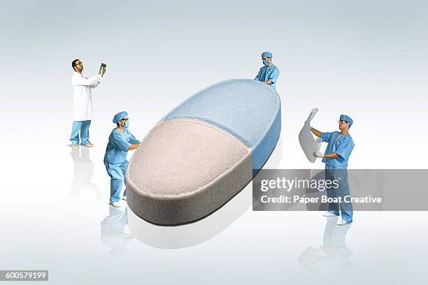 scientists holding a giant blue and white pill - one in four people stock pictures, royalty-free photos & images