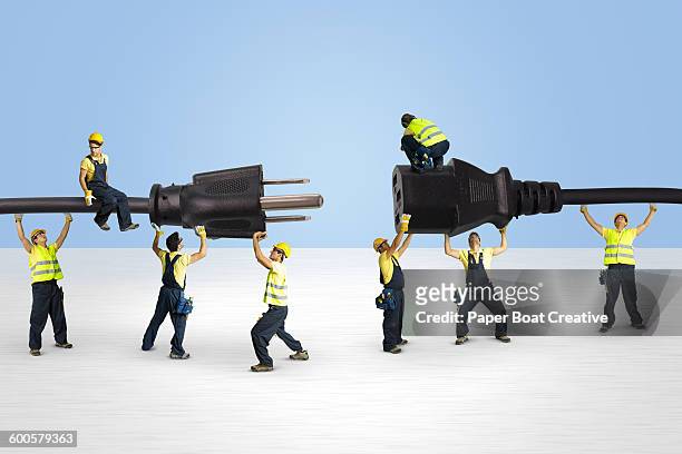 group of men holding electric plugs and joining it - piccolo foto e immagini stock