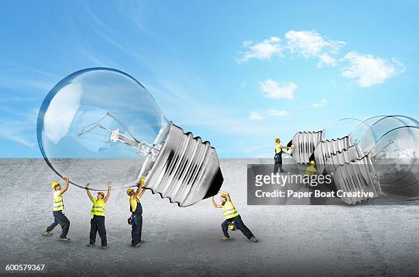 tiny builders carrying a bunch of lightbulbs - big idea foto e immagini stock