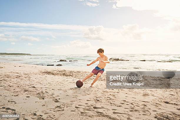 teenage boy playing soccer on beach - sand trap stockfoto's en -beelden
