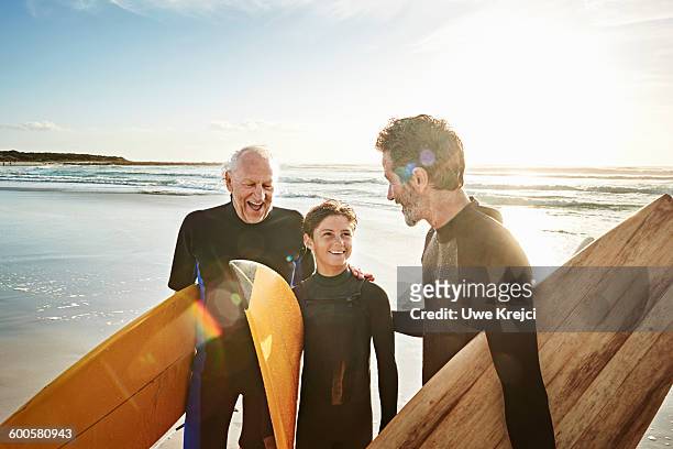 grandfather, father and son surfing - hispanic man on beach stock-fotos und bilder