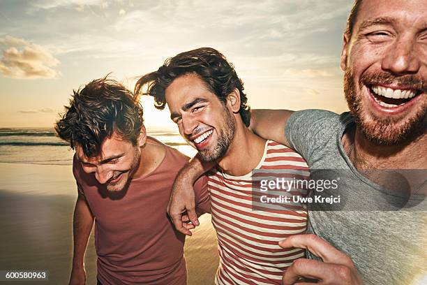 three male friends on beach, smiling - guys hanging out foto e immagini stock