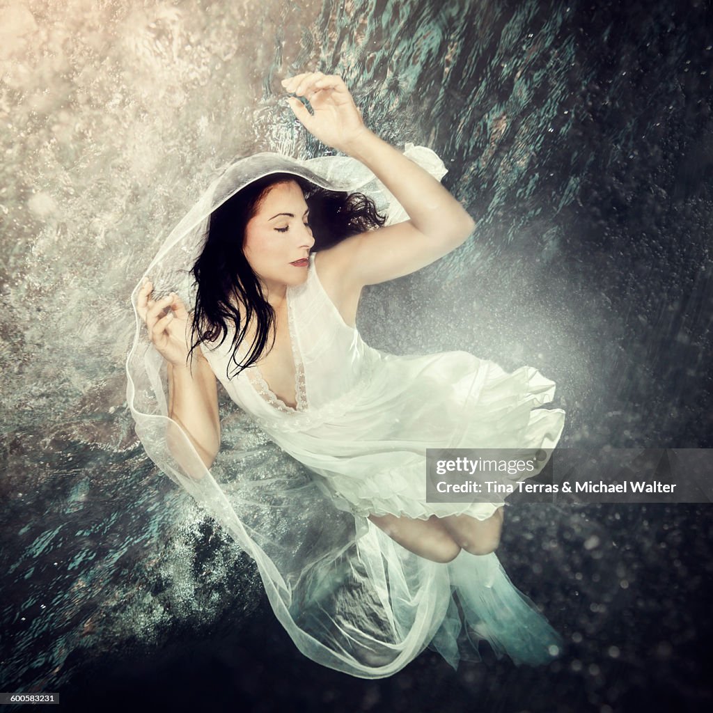 Woman in wedding dress floats underwater