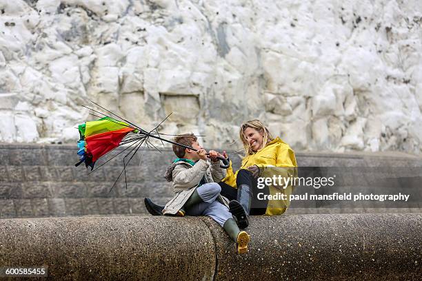 mother and son with broken umbrella - broken umbrella stockfoto's en -beelden