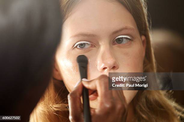 Stylist works on a model's makeup backstage during the Noon By Noor fashion show during New York Fashion Week: The Shows September 2016 at The...