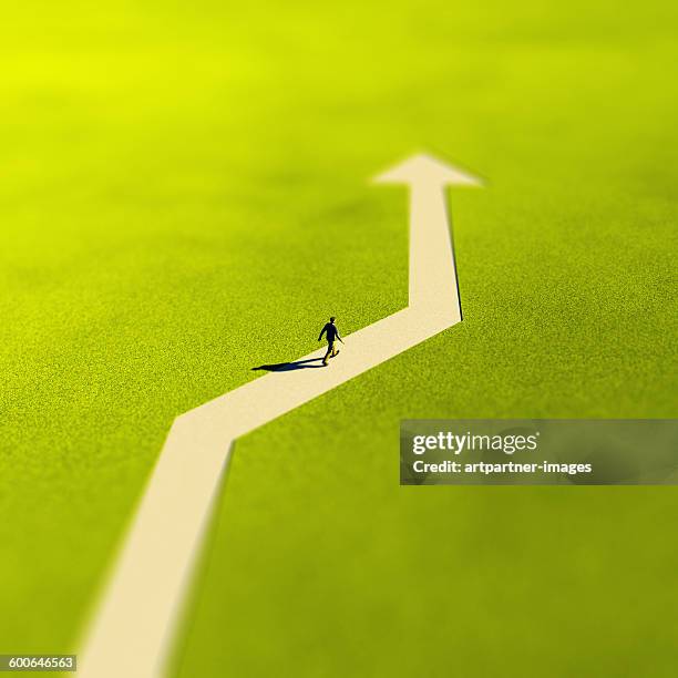 man walking on an arrow shaped path - abkürzung stock-fotos und bilder