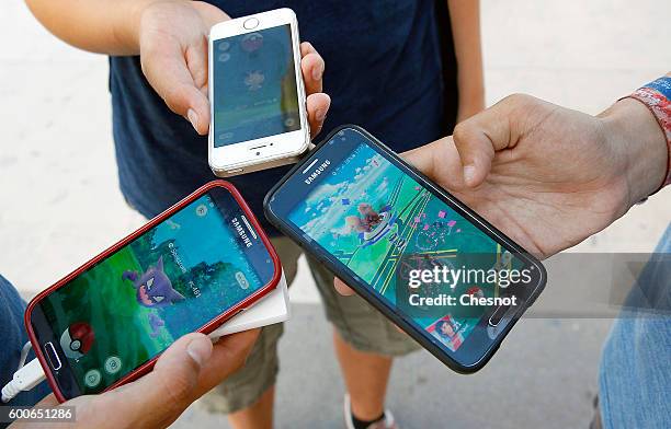 Kids show the screen of their smartphone with Nintendo Co.'s Pokemon Go augmented-reality game at the Trocadero in front of the Eiffel tower on...