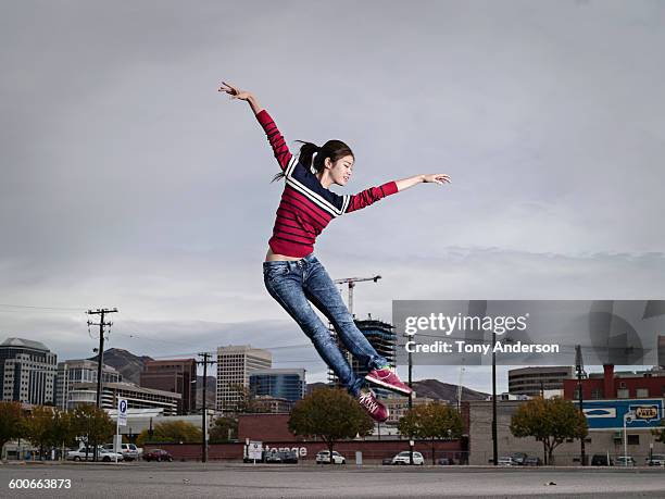 young woman jumping for joy city in background - red car wire 個照片及圖片檔