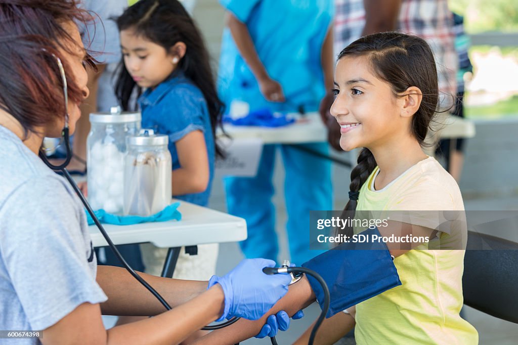 Young Hispanic patient getting blood pressure checked by nurse