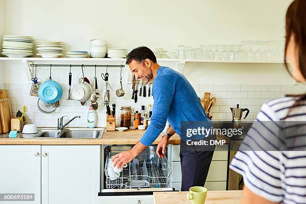 reifen mann setzen kaffeebecher in der spülmaschine - spülmaschine stock-fotos und bilder