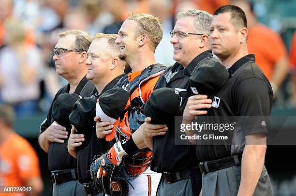 Caleb Joseph of the Baltimore Orioles and the umpire crew stand for the national anthem before the game against the New York Yankees at Oriole Park...