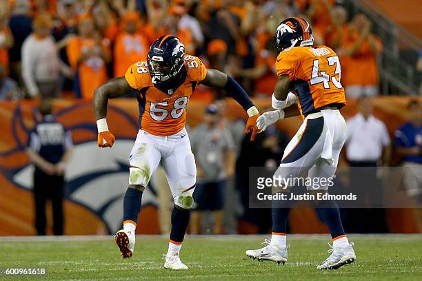 Outside linebacker Von Miller and strong safety T.J. Ward of the Denver Broncos celebrate a Miller sack against the Carolina Panthers late in the...